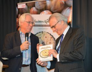 Burgemeester Van Aartsen (rechts) ontvangt het eerste exemplaar van het boek met de geschiedenis van banketbedrijf Maison Kelder. Oud-eigenaar Lucas Jonker (links) trad op als opdrachtgever.